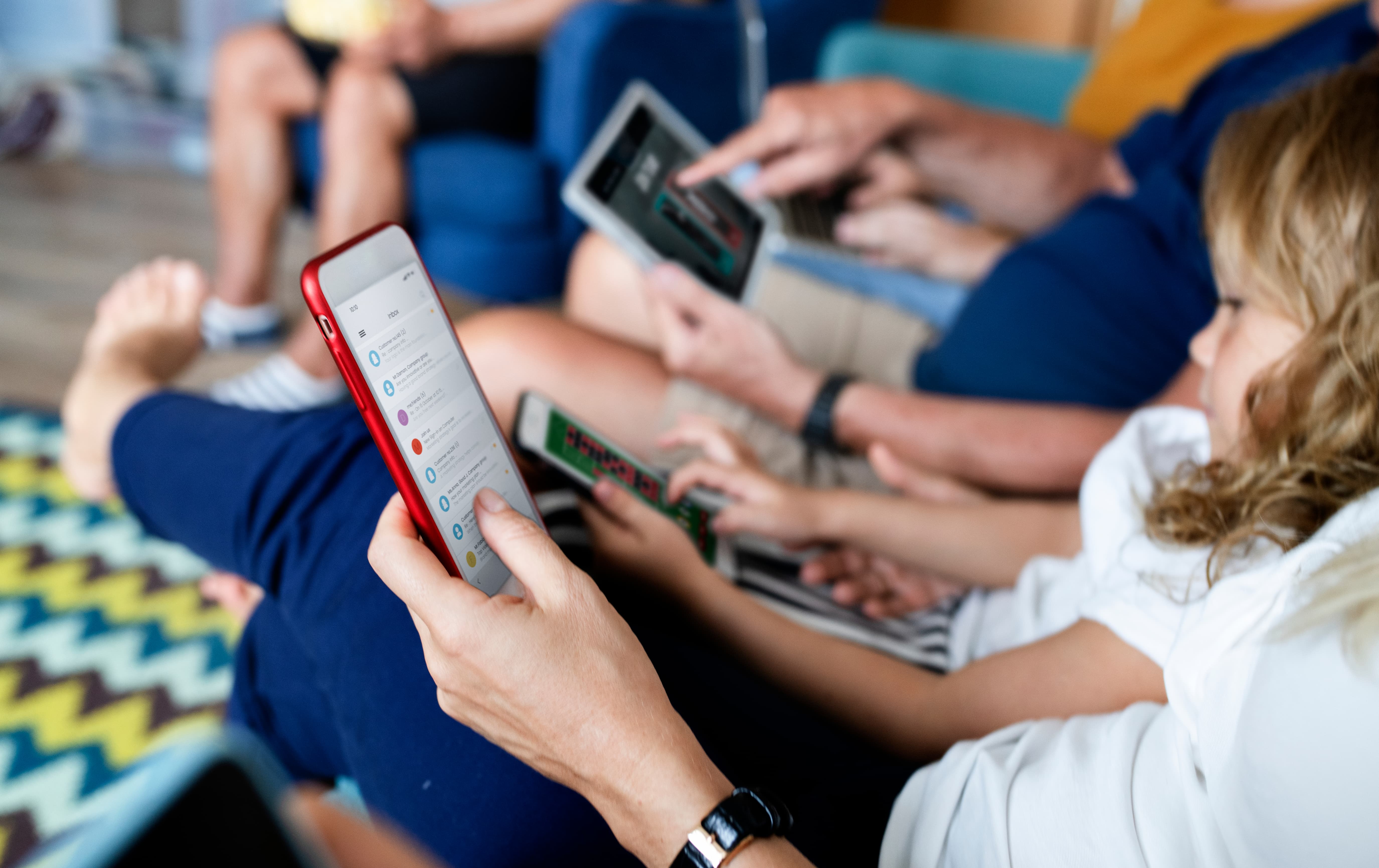 A child sits in an adult's lap as both of them use individual smart phones