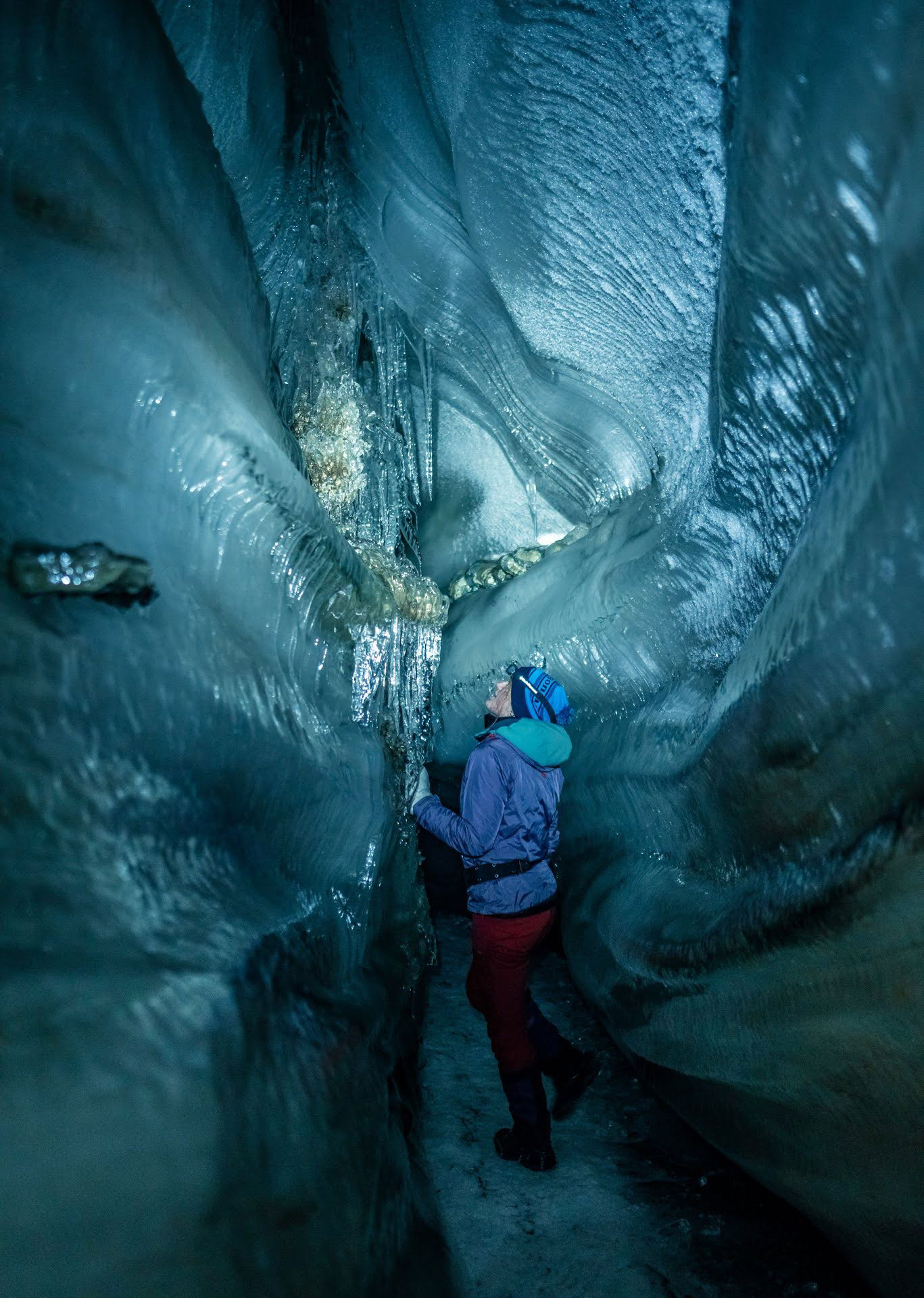 A woman stands inside of a glacier. 