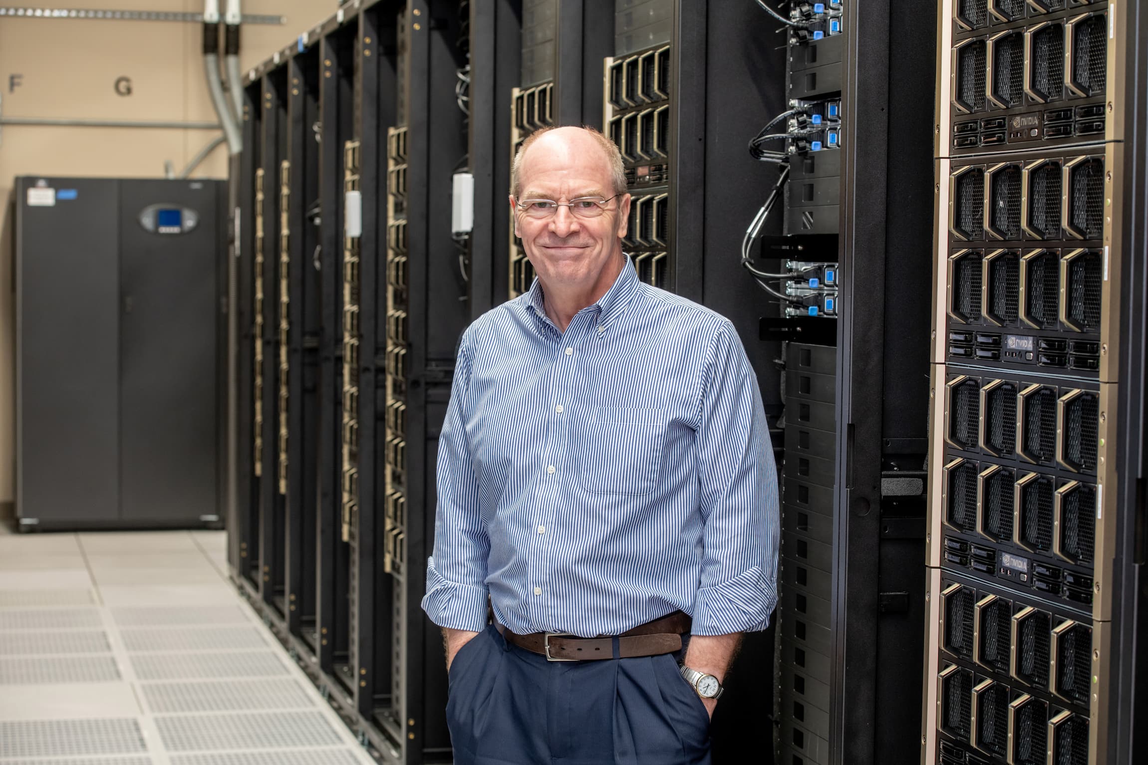 A man standing in front of a series of machines that comprise the UF HiPerGator supercomputer. 