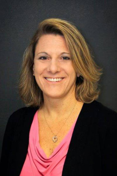 Image of woman wearing black jacket and pink blouse.