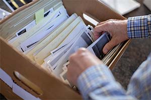 A photo of a man's hands as he sifts through papers in a box.