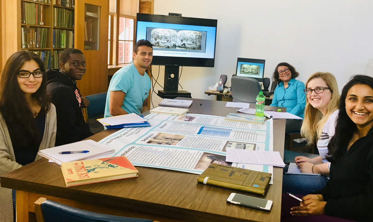 Students sitting around a table with a research poster in the middle