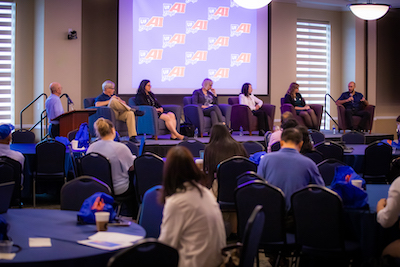 Photo of stage with people speaking about AI at UF