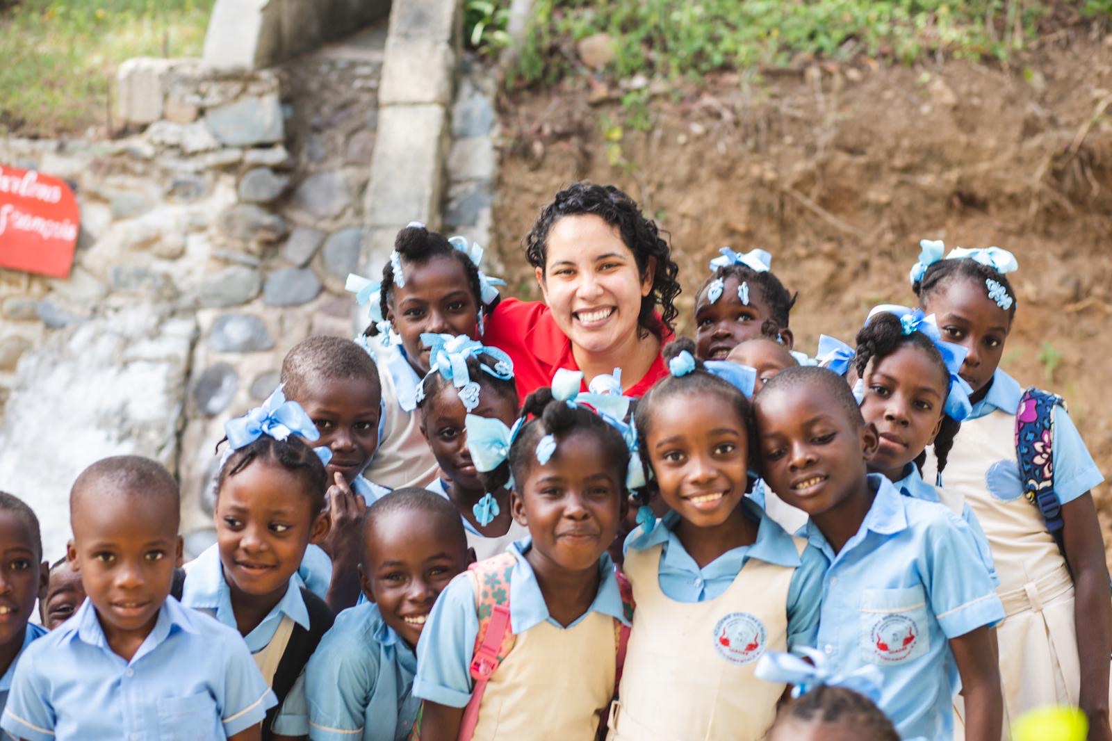 A woman poses with a group of schoolchildren.