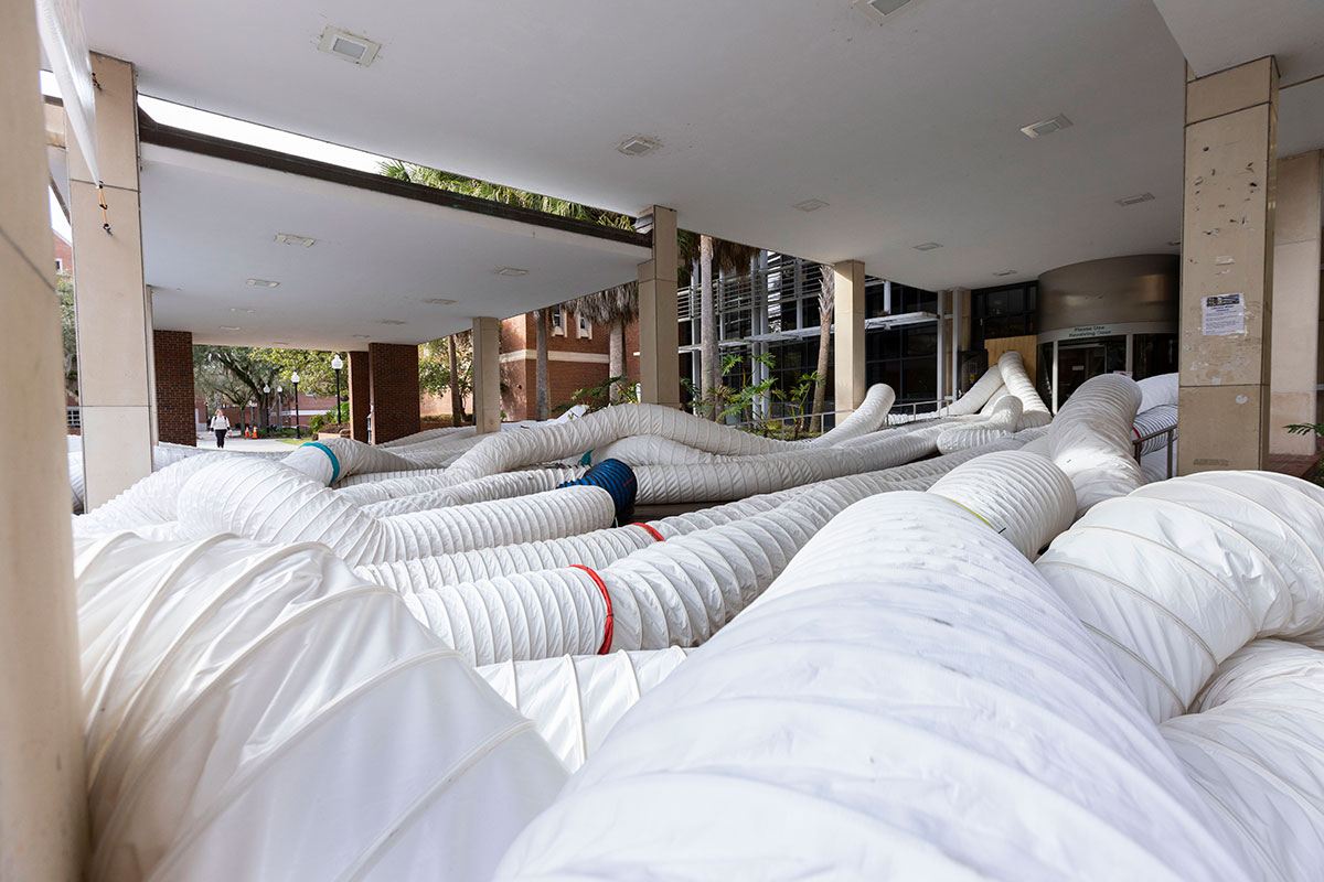 An image of large, white tubes used as part of restoration entering through the front doors of the Library West