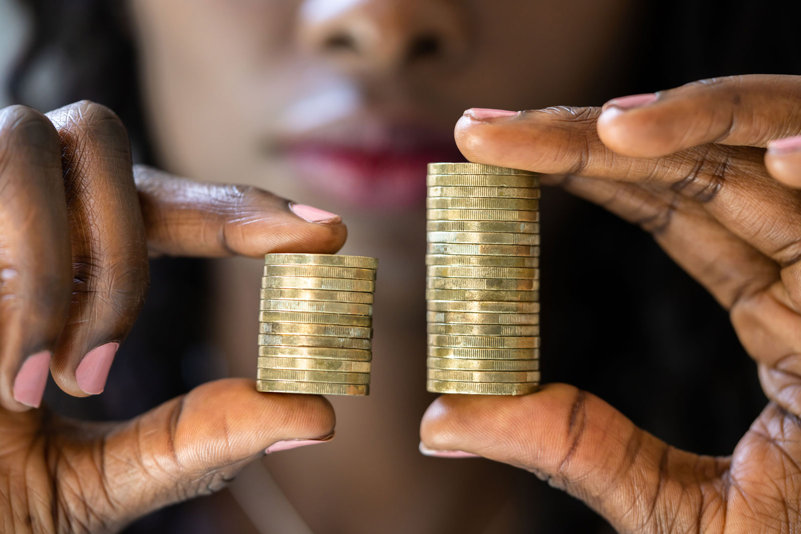Close up of a person's hands holding more coins on the right than the left