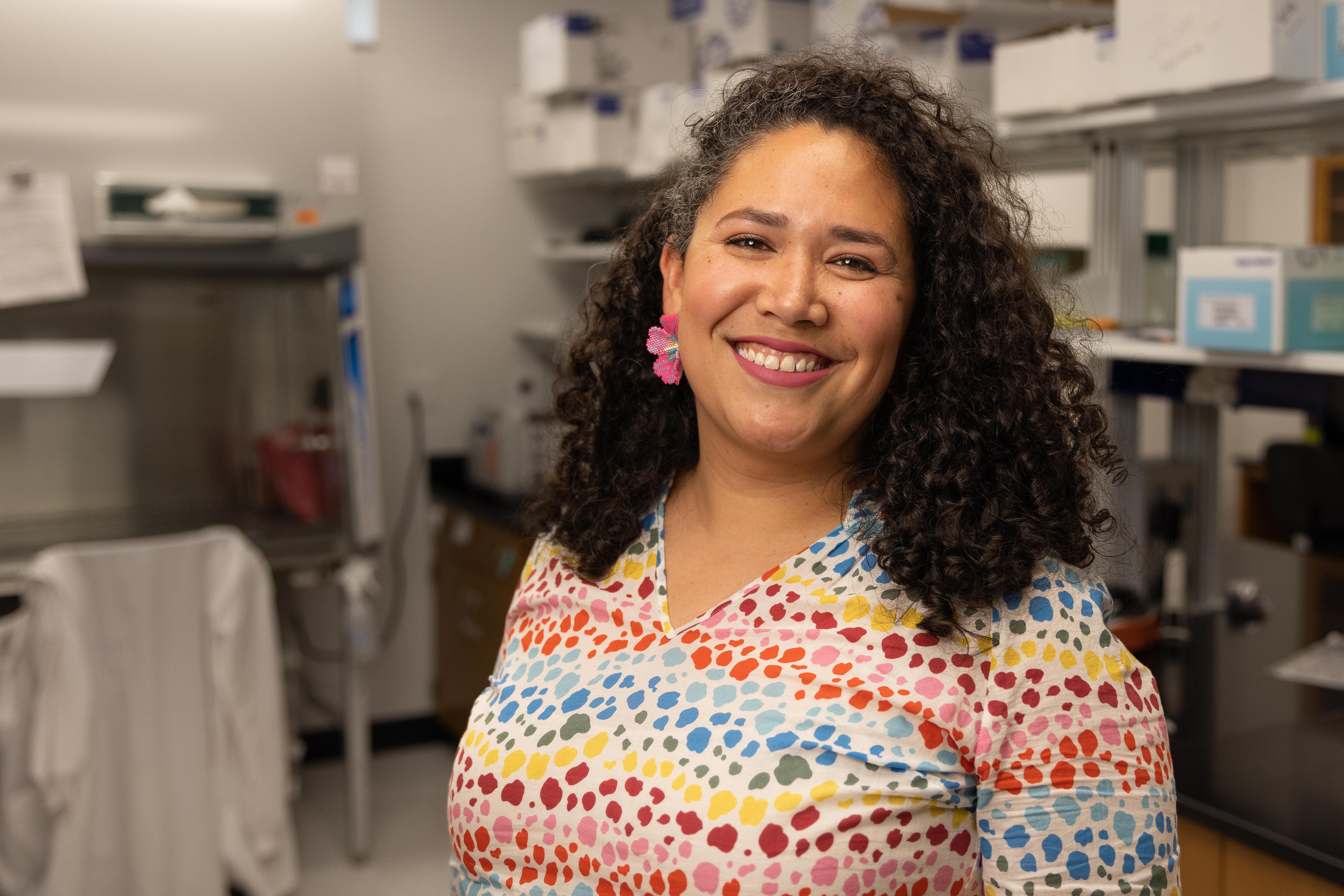 A female faculty member standing and wearing a colorful top..