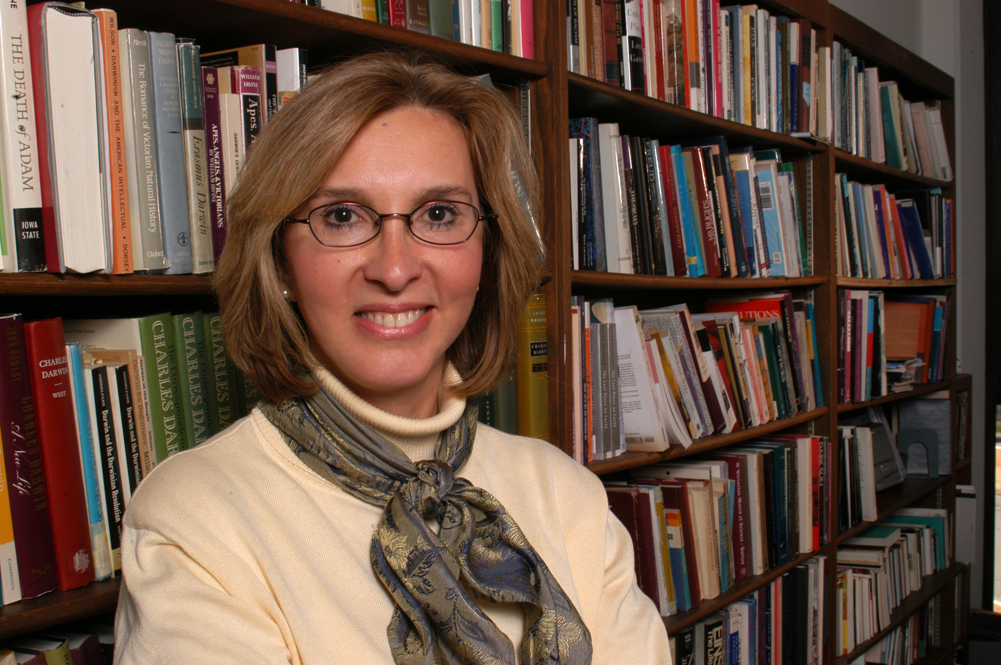 A female faculty standing in front of a bookcase. 