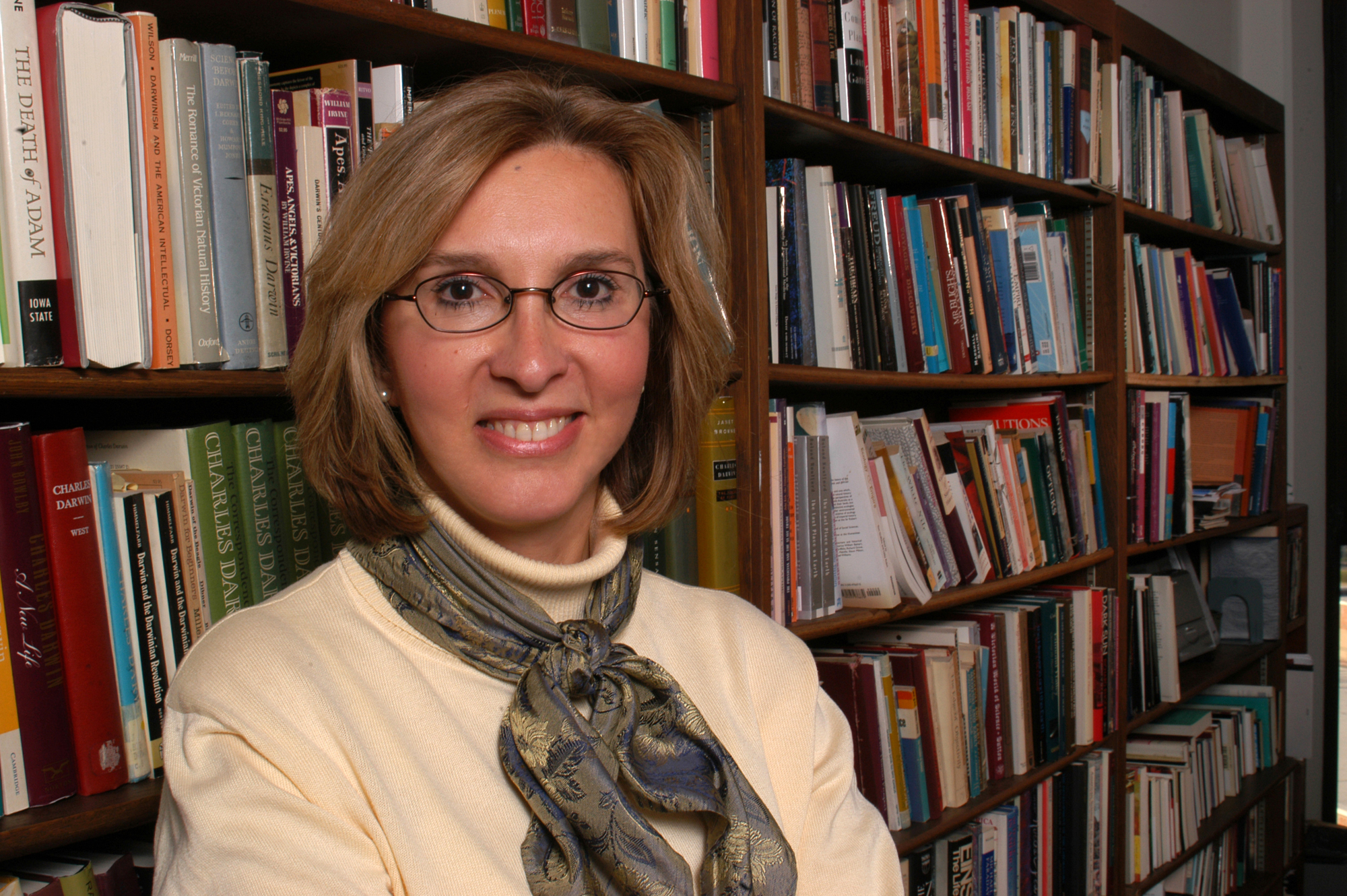 A female faculty standing in front of a bookcase.