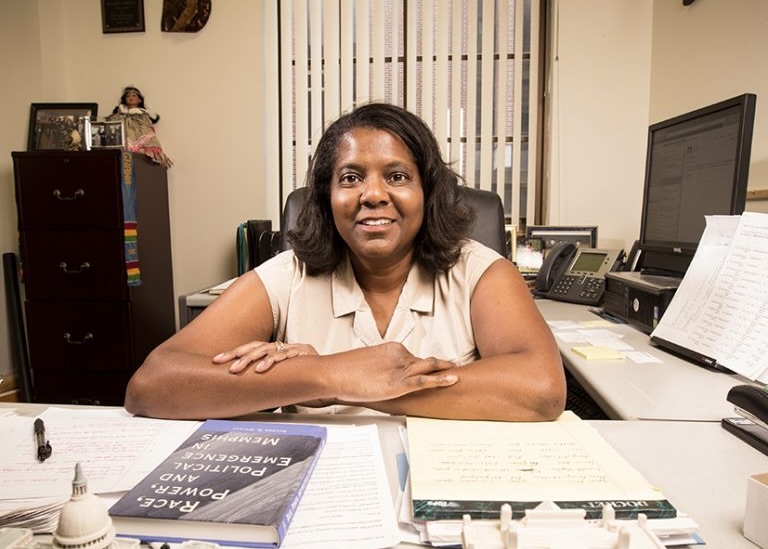 A female faculty member sitting behind a desk.