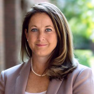 A headshot of a woman in a gray suit.