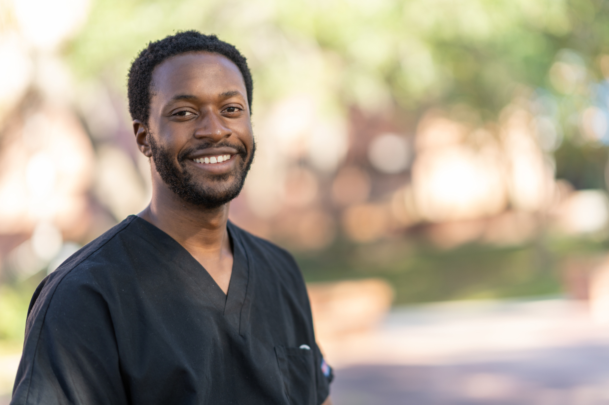 A headshot of a man in black scrubs.