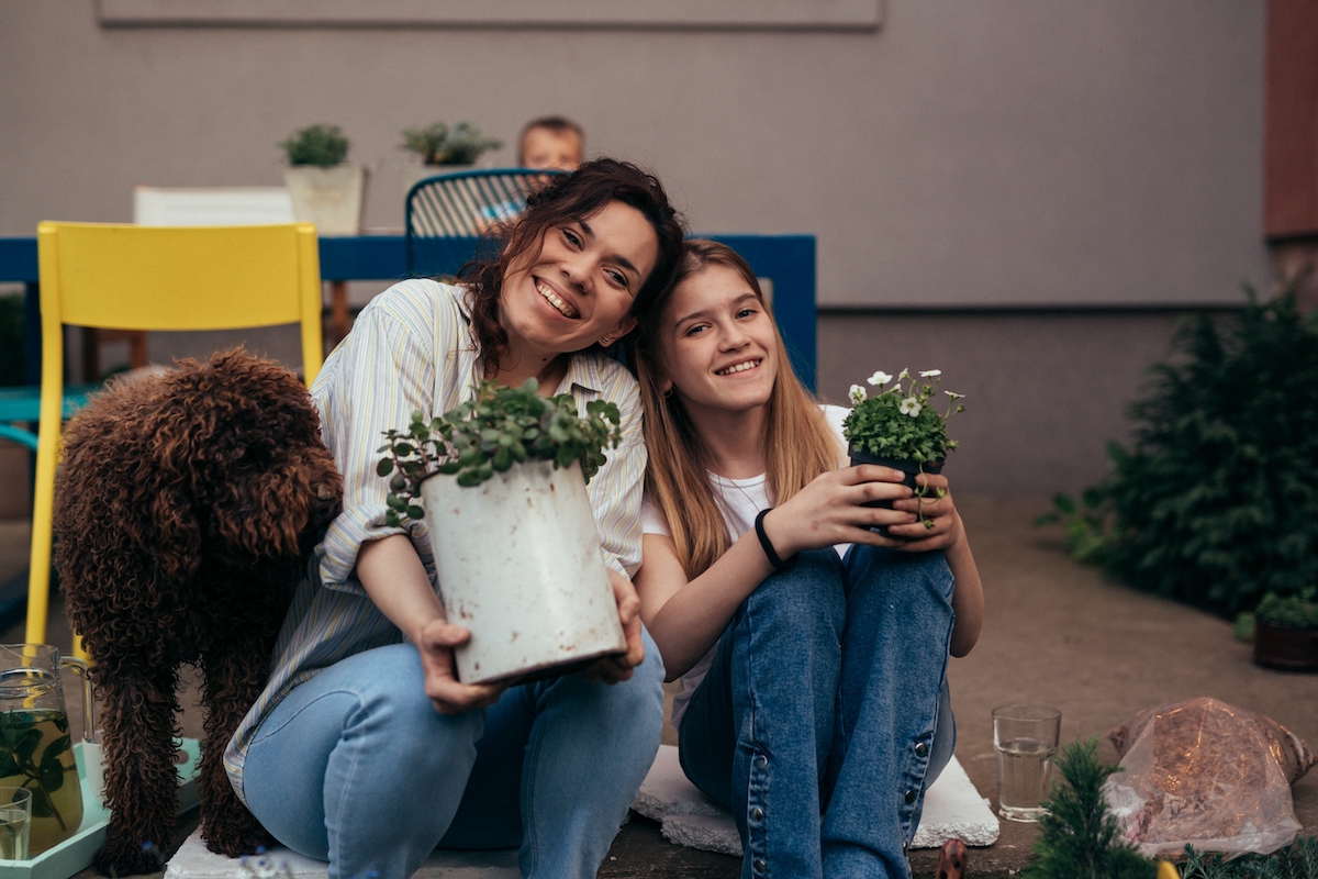 a mom and daughter each holding a potted plant