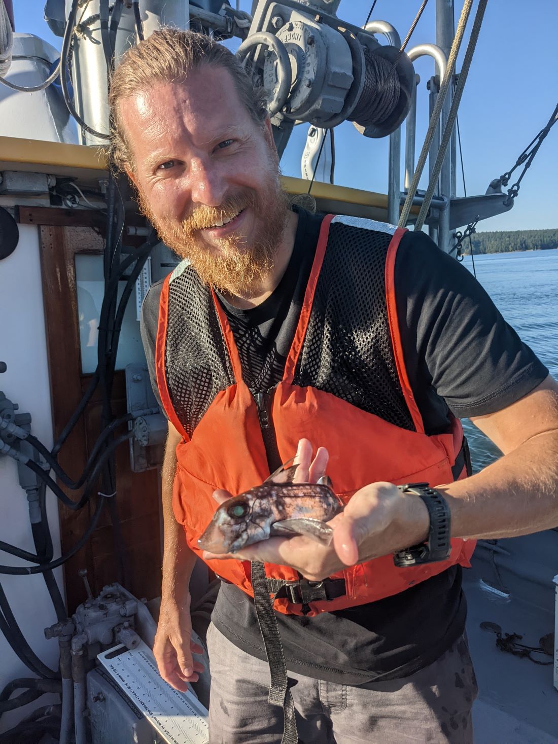 Scientist on a boat holding a ghost fish in his hand for camera