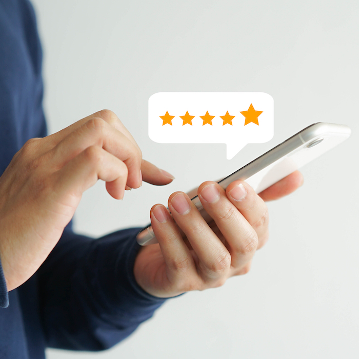 A person holding a smartphone while tapping out a five star review