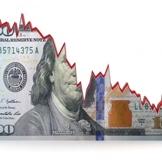 A one hundred dollar bill cut in half by a declining stock graph