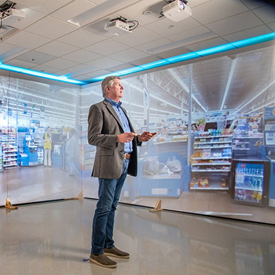 UF's Read Hayes stands in front of video screens projecting interior retail story