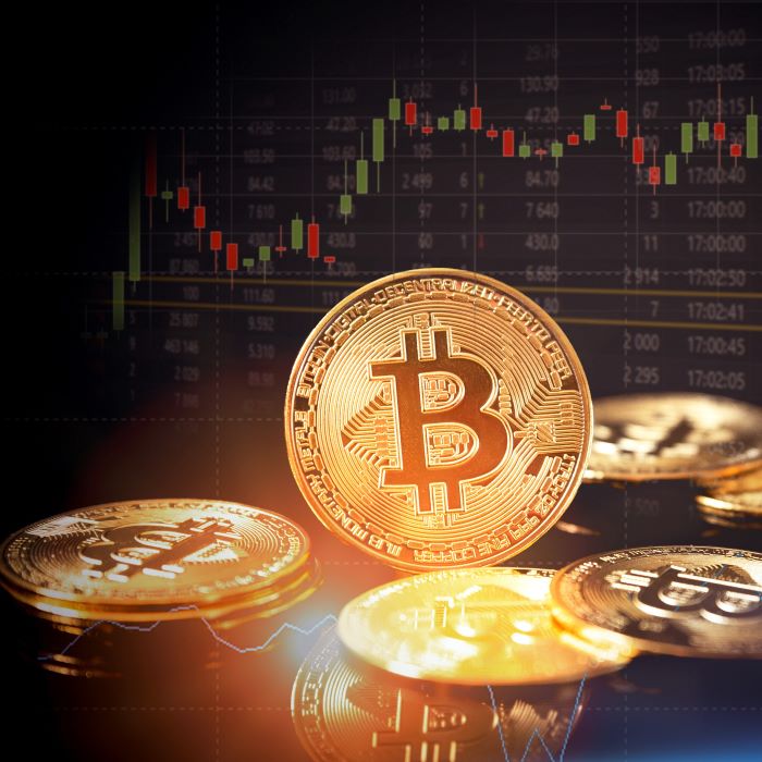 Several artists rendering of gold bitcoins with the bitcoin logo and market prices visible in the background