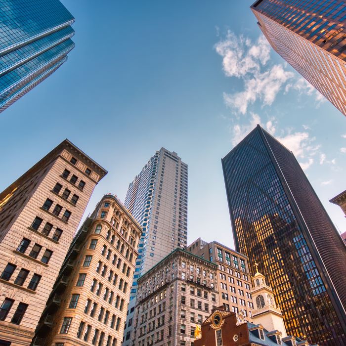 From a low angle looking up at several sky scrapers against a blue sky