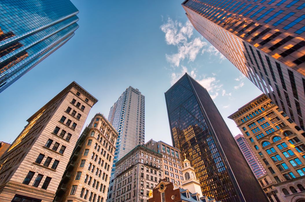 From a low angle looking up at several sky scrapers against a blue sky