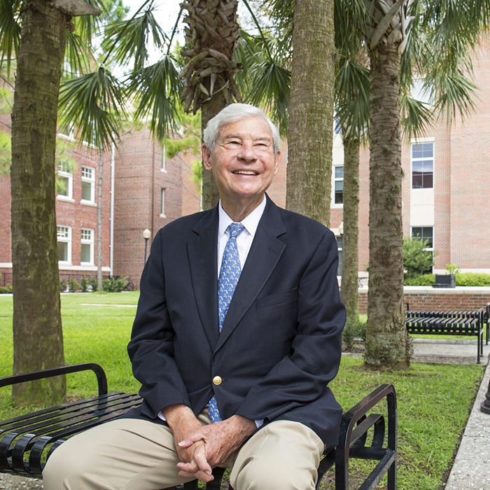 Former Sen. Bob Graham sits on a bench before Pugh Hall at the University of Florida.