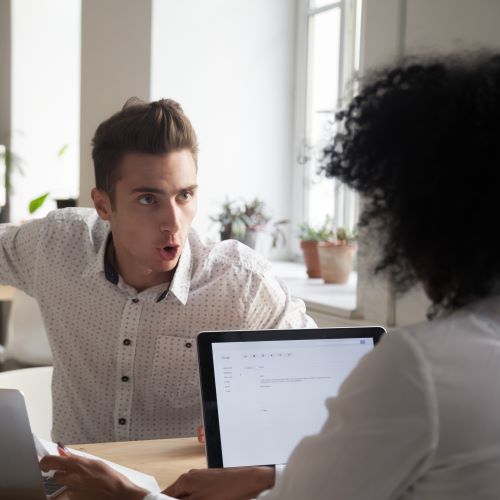 A man is yelling at his female coworker across a table