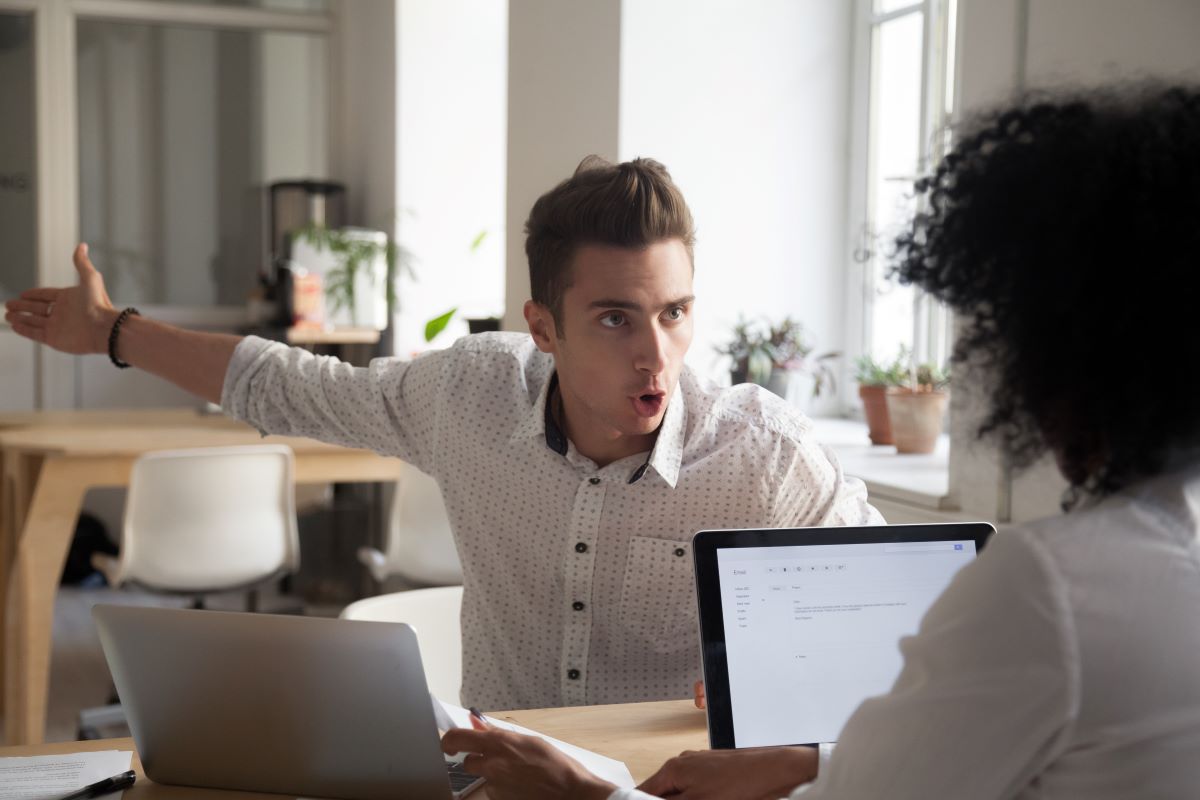 A man is yelling at his female coworker across a table