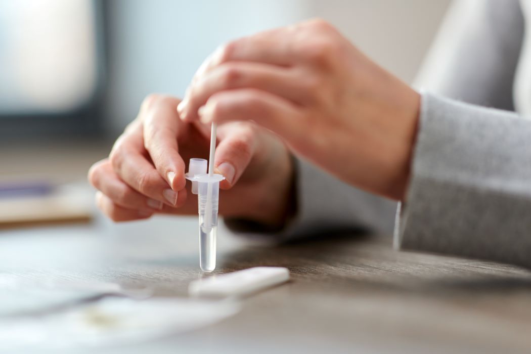 A close up of a woman's hands mixing a sample in a small test tube