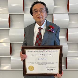 Jacob Chung standing holding an award from NASA