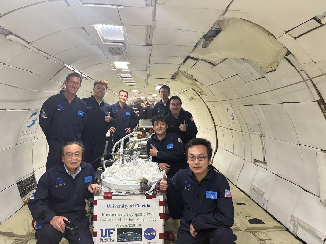 Researchers in flight suits pose with research equipment inside the empty cabin of a plane