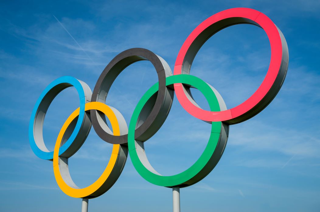 A statue of the five olympic rings against a blue sky