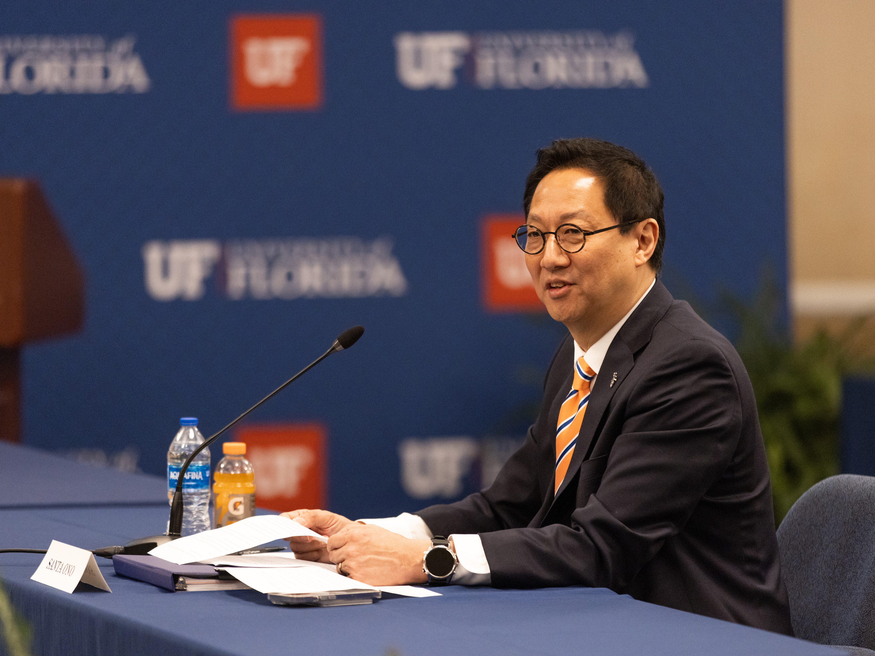 Santa Ono speaking while sitting at a table.