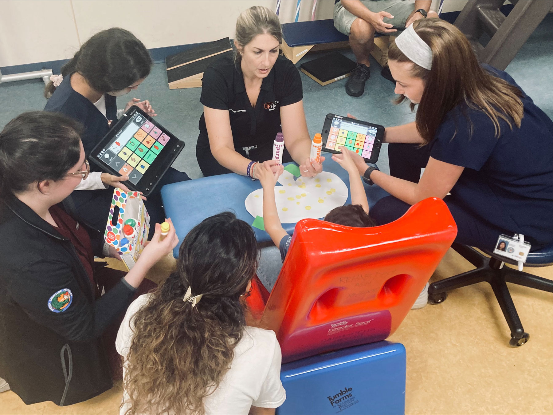 UF Health speech language pathologist Jaime Miale works with a young patient on using assistive communication devices