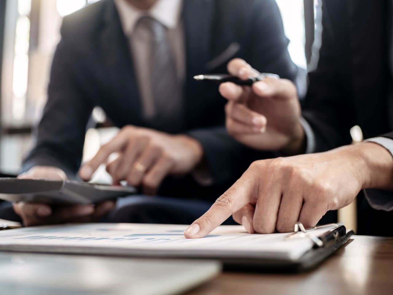 A woman points at financial documents while a man holds a calculator