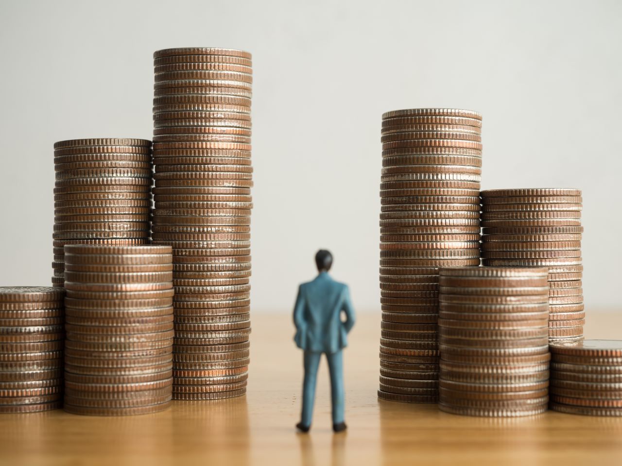 A plastic figurine of a man gazing at stacks of quarters on a table