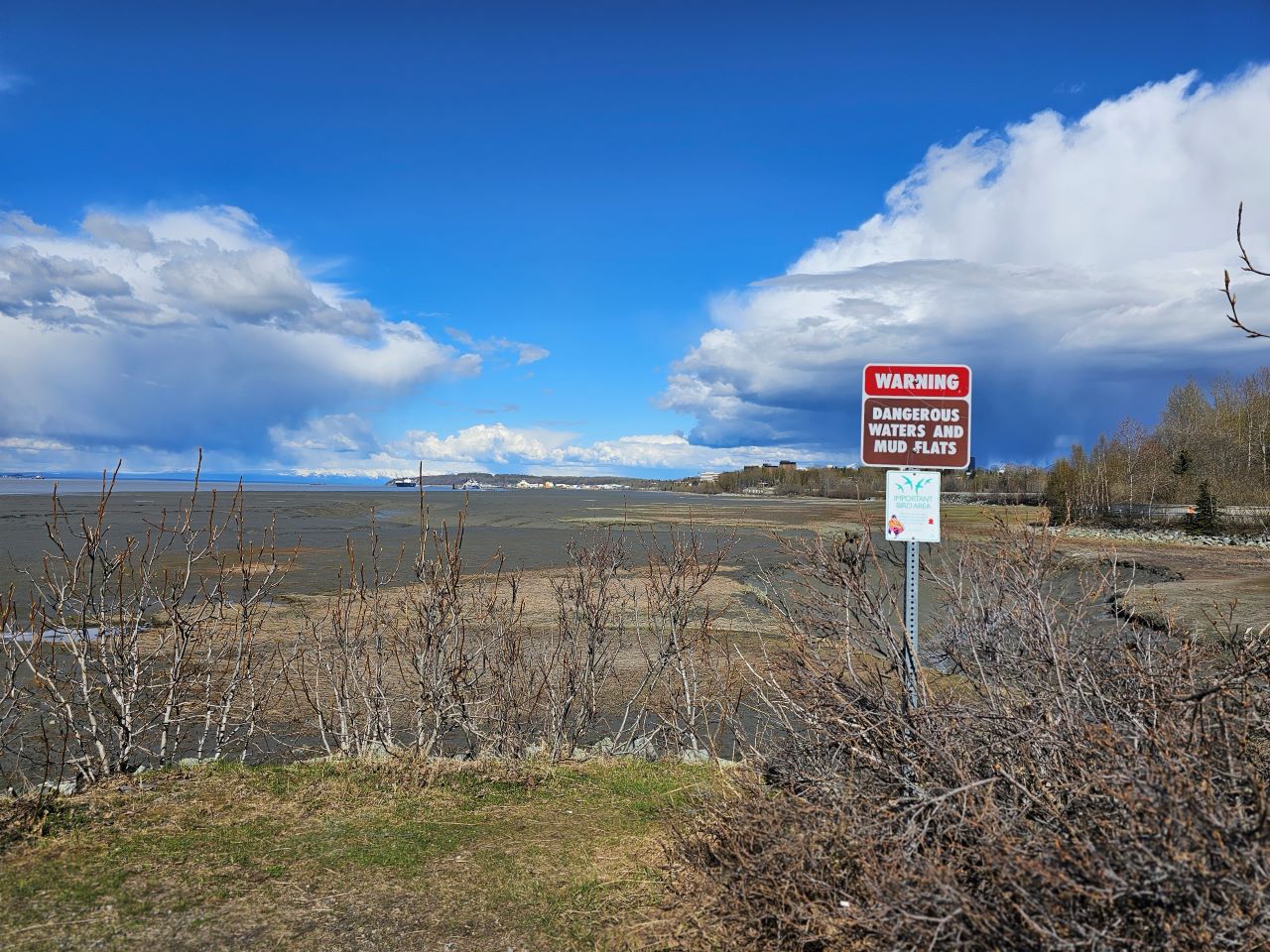 landscape view of a mudflat with a danger sign in the foreground