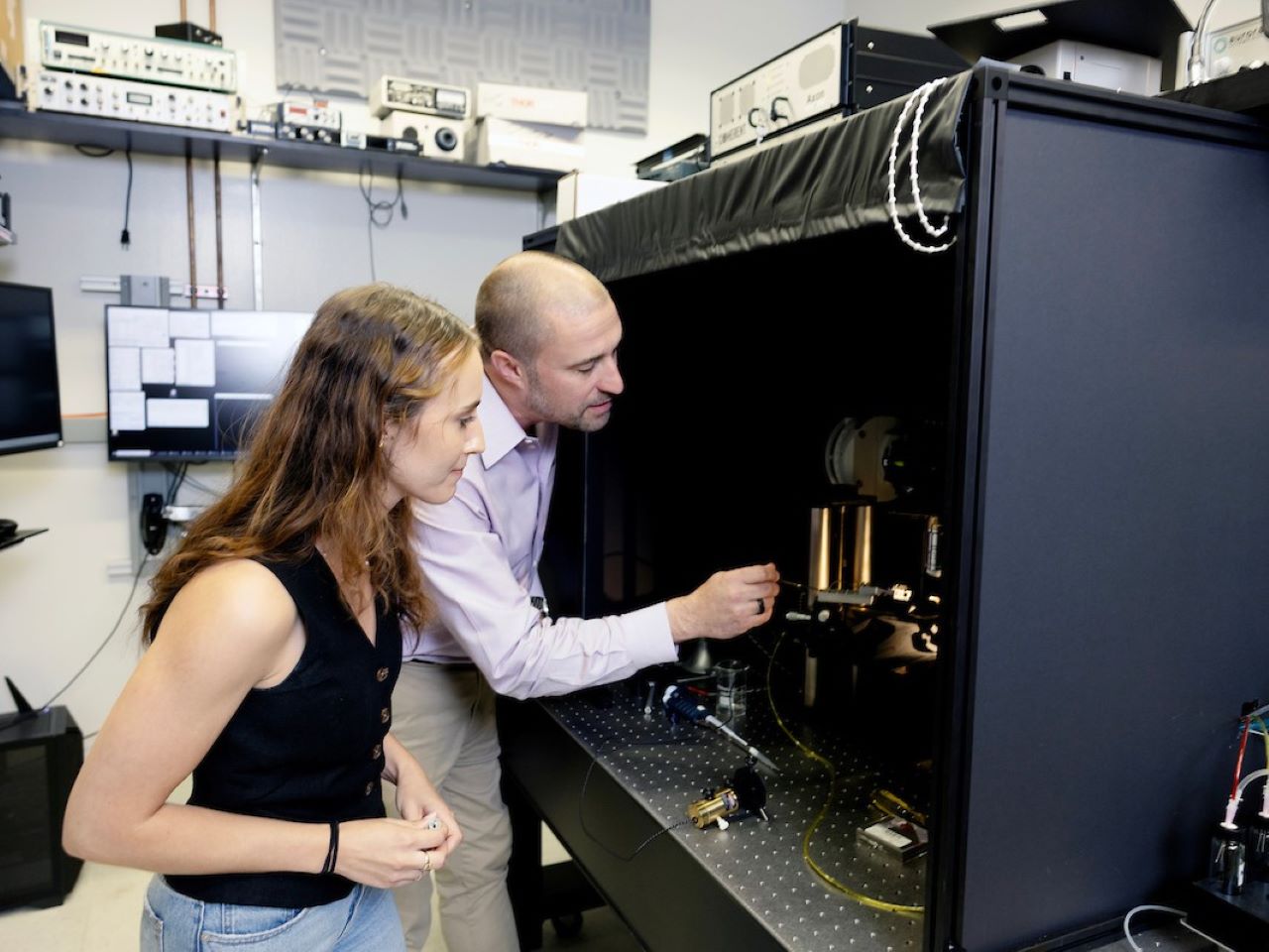 Two researchers peer into an experimental device