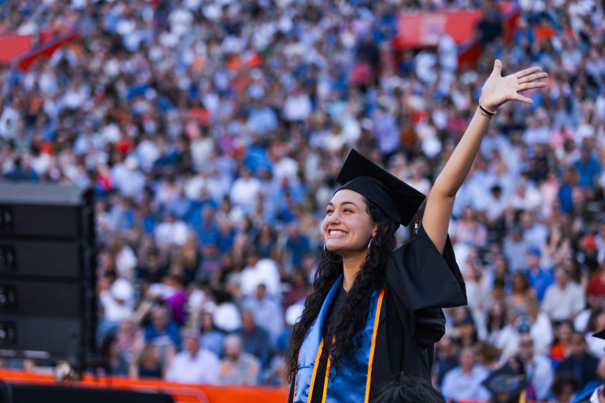 A female graduate at commencement with arm raised