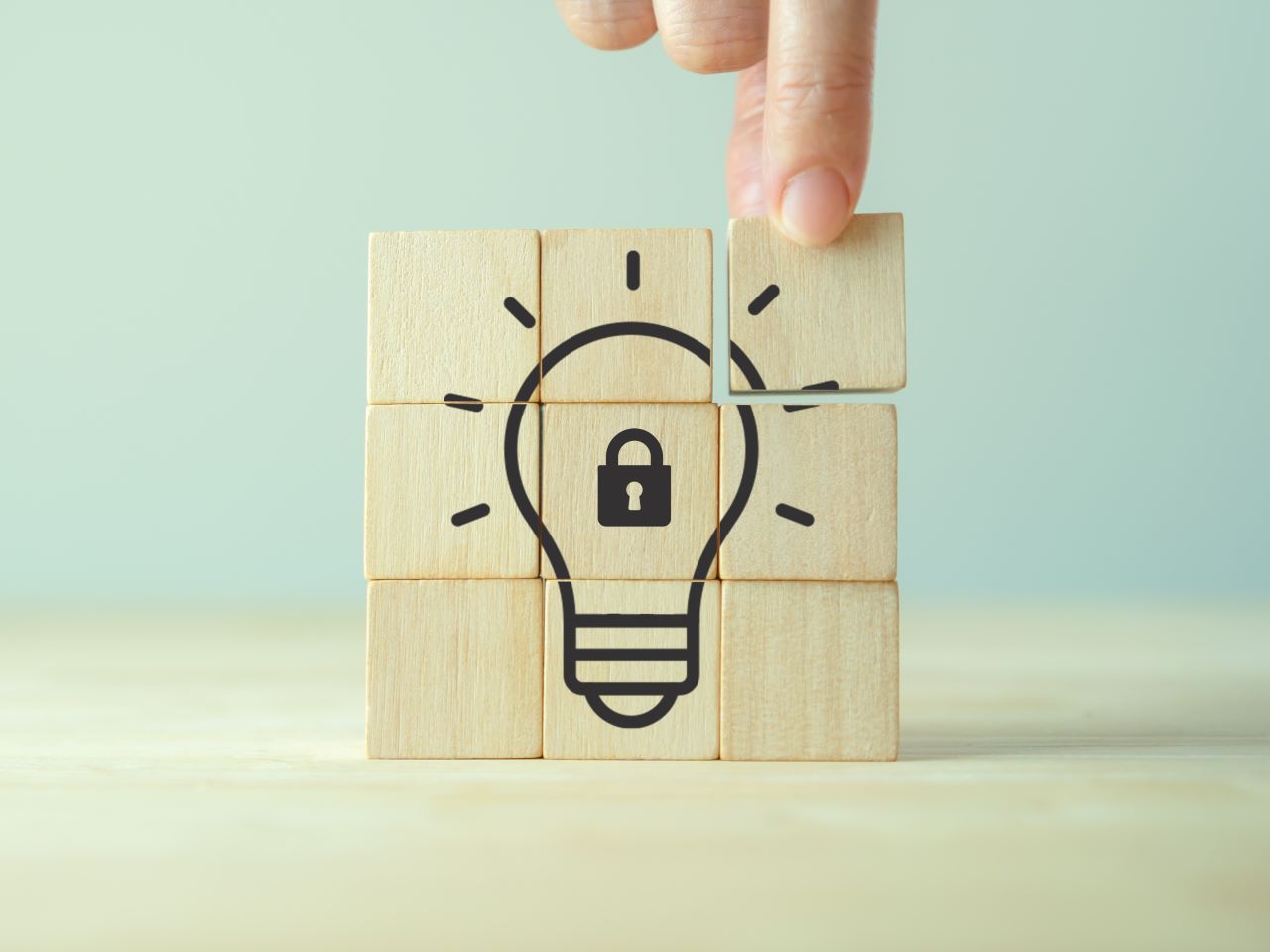 A wood block with a drawing of a lightbulb with a padlock inside