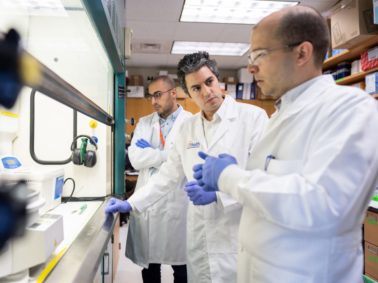 Elias Sayour in a white lab coat with two other scientists