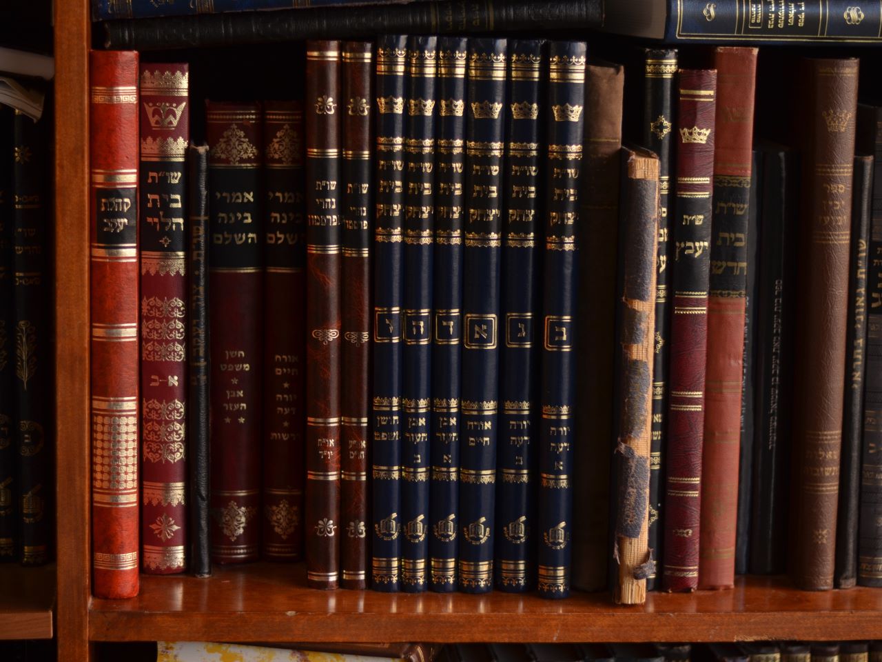 A shelf of leather-bound books with Hebrew characters on them