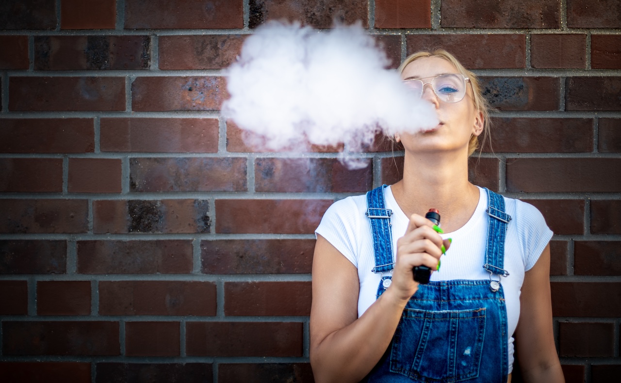 young adult blowing smoke from a vape