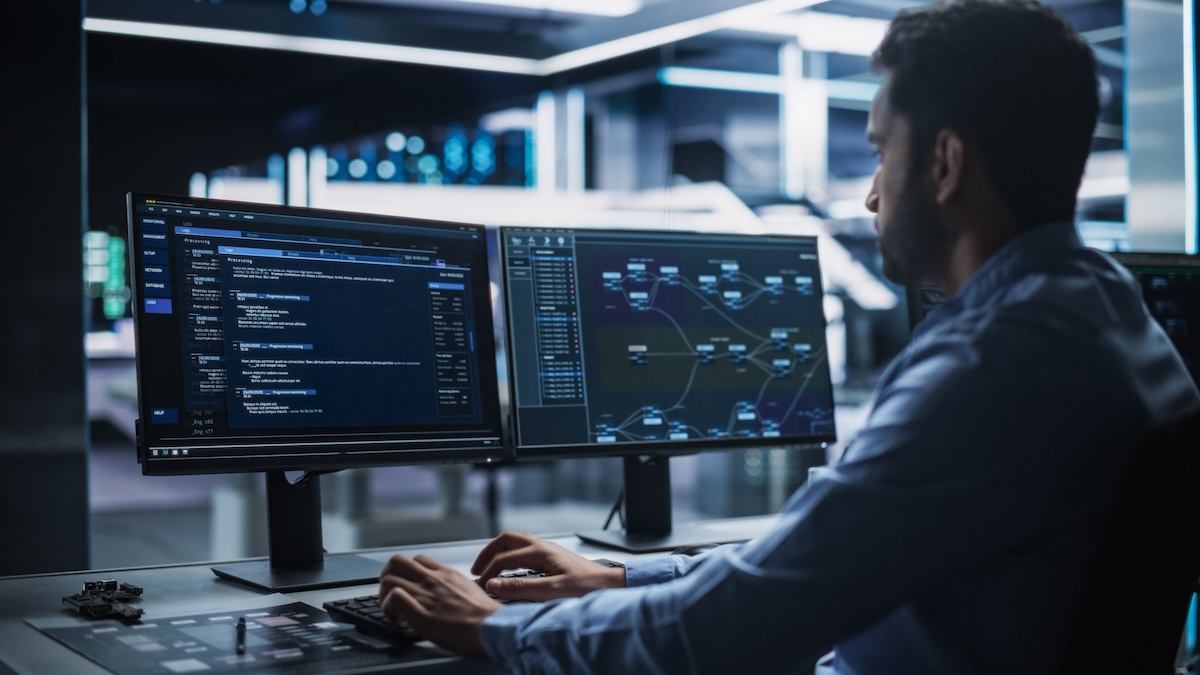 a man at the keyboard of computer in dark room