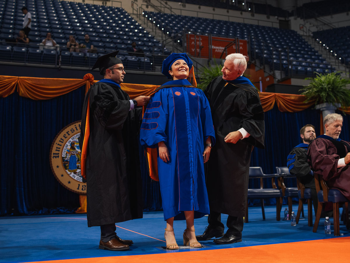 A doctoral graduate gets hooded at graduation ceremony.