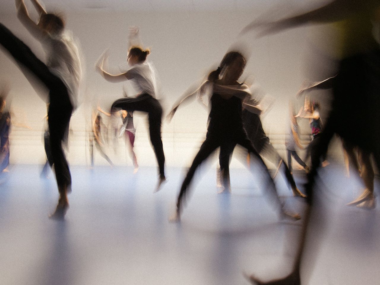 Dancers rehearsing a contemporary dance blurred out by their motion