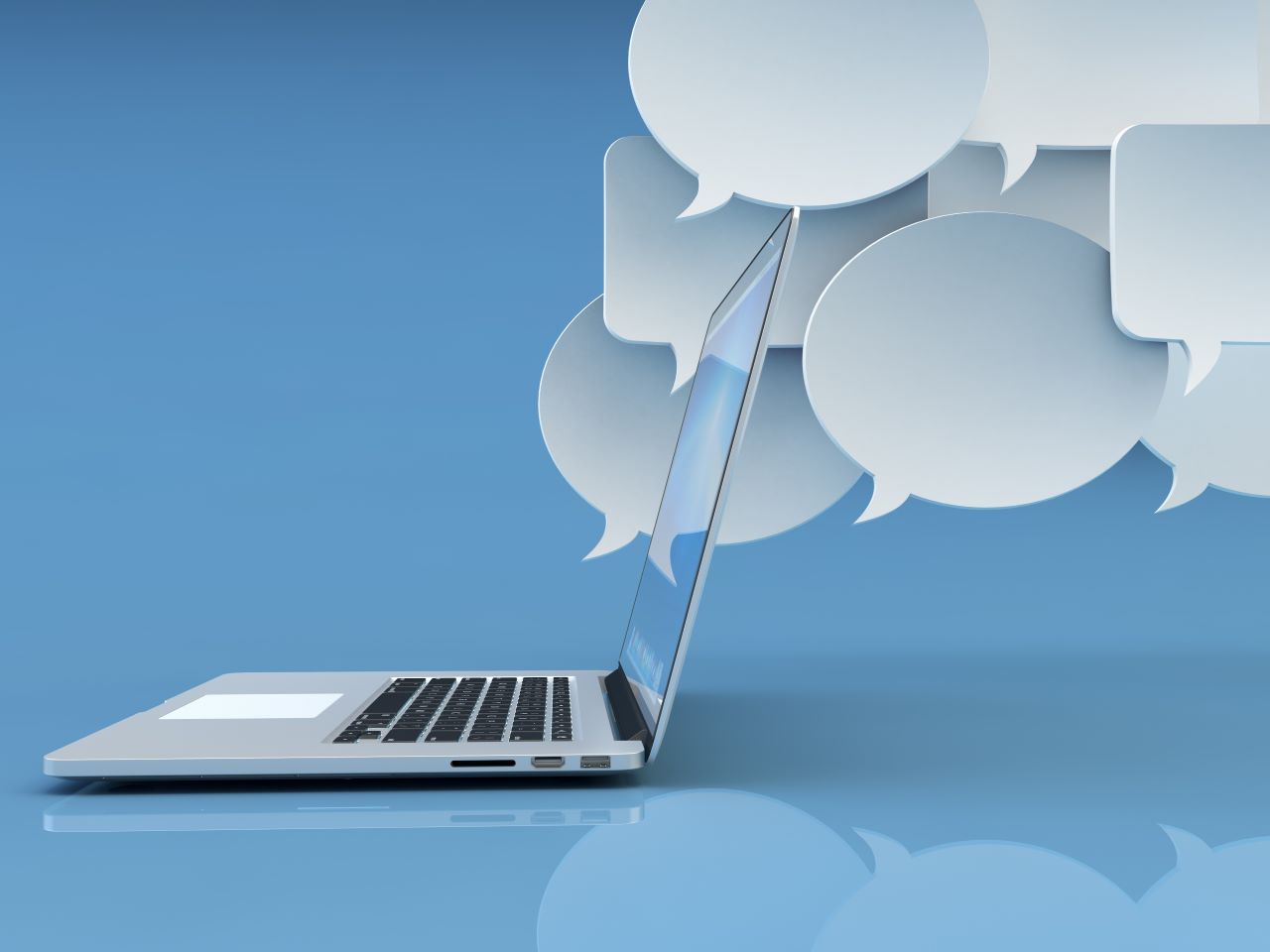 An open laptop in front of several white message bubbles