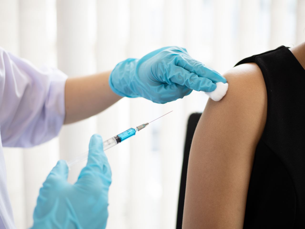 Gloved hands provide a vaccine shot in a woman's arm