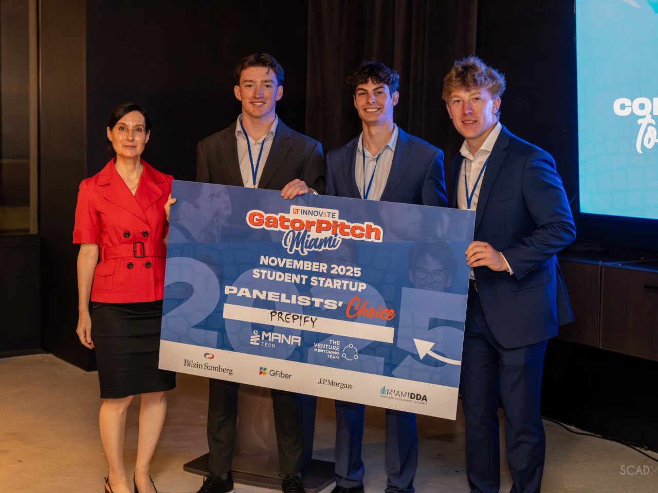 A woman and three young men holding a large poster board saying Gator Pitch and a company name
