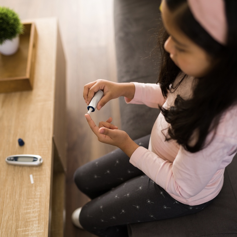 A stock image of a child checking glucose levels.