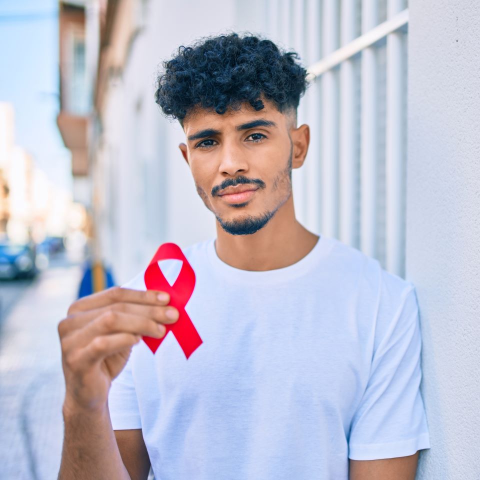 A young man holding a red HIV ribbon
